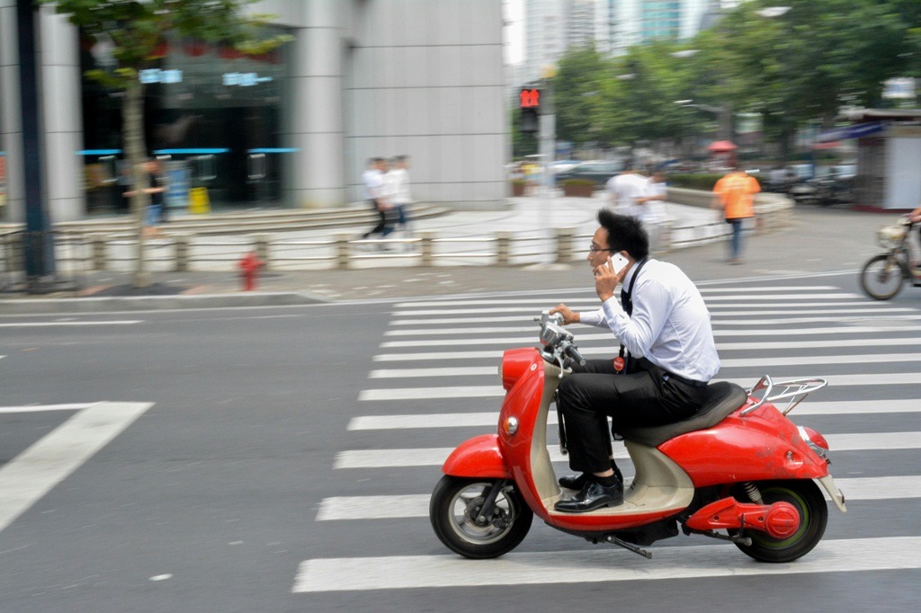 Motorcycles South Africa 2026 - Businessman riding a red scooter while talking on the phone in Shanghai, China